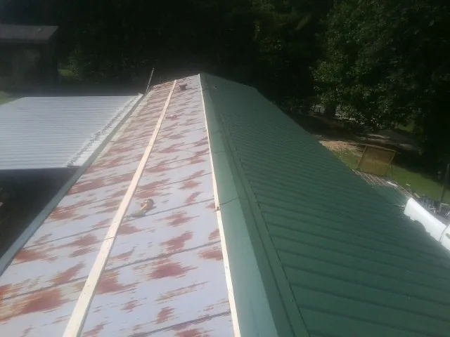 Old rusted panels beside newly installed green metal roofing — Wind Damage Roof Repair by Roofing Brothers in Andover
